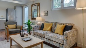 Una sala de estar con sofá, sillón, mesa de centro y lámpara.