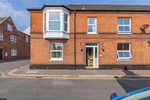 A two-story brick building with a corner bay window, a front door labeled "CAM HOUSE," and a satellite dish on the roof. - 2 Bed in Cromer (oc-s32971) (Cromer)