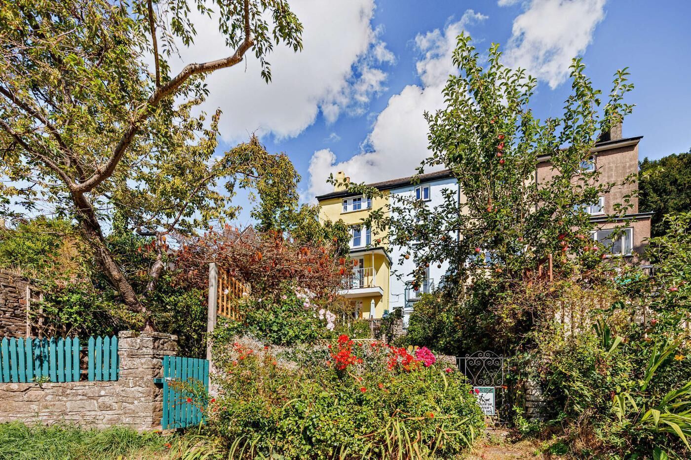 Un quartier résidentiel composé d’une rangée de maisons à deux étages, d’un mur en pierre et d’un portail en métal.