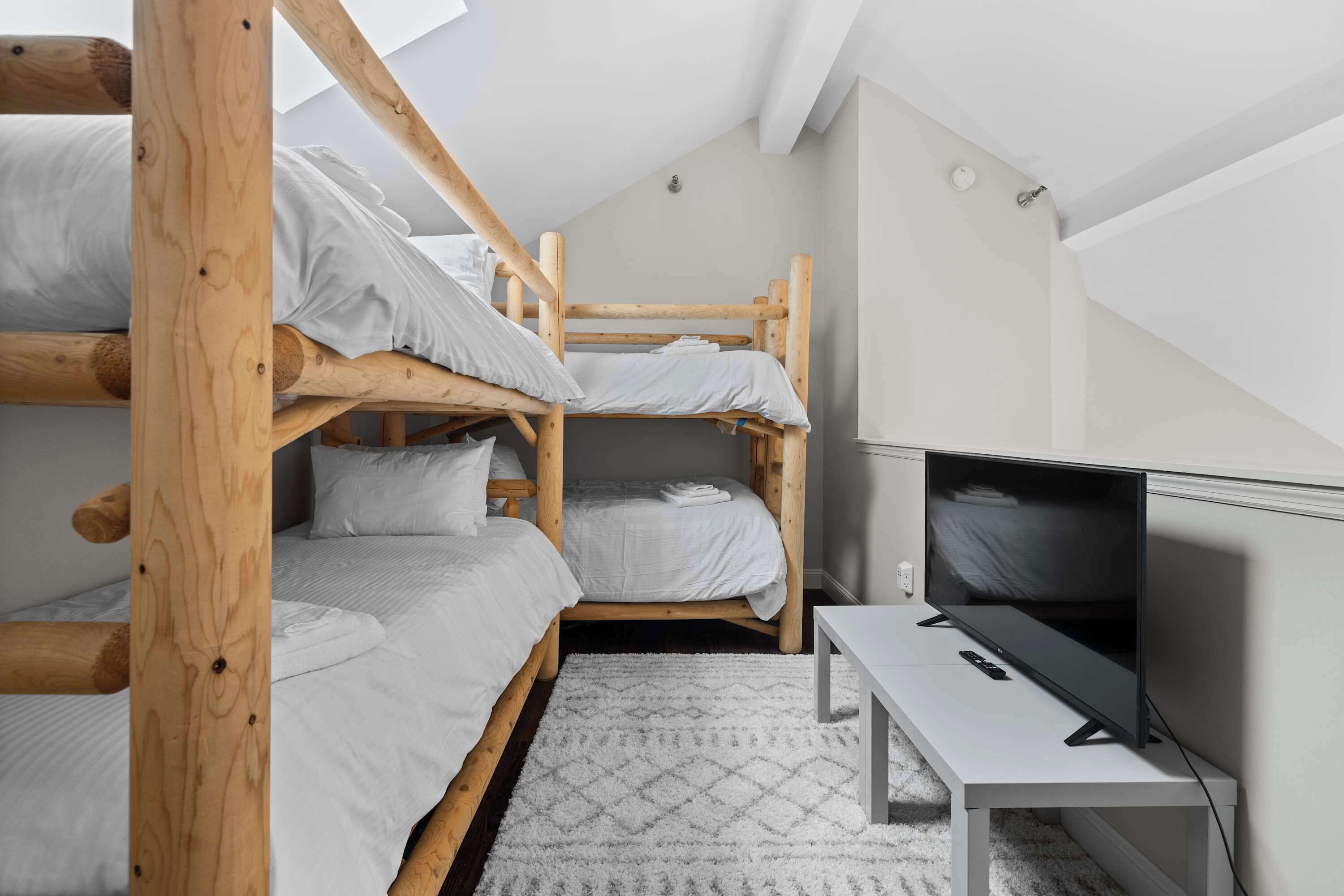 Une chambre de type dortoir avec des lits superposés, un téléviseur à écran plat et une petite table.