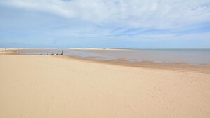 Une vaste plage de sable fin, avec des vagues douces et un ciel dégagé.