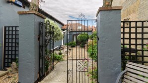 Une courClose, accessible par un chemin pavé qui mène à un bâtiment doté d’un toit en tuiles.
