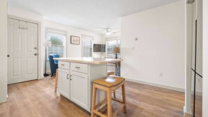 A kitchen with wooden flooring, white cabinets, a bar stool, and a ceiling fan. - Bright 2BR Escape 2 Min to Okemo, Walk to Downtown (Ludlow)