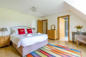 Une chambre à coucher comprenant un lit, une commode, une chaise, un miroir et une porte donnant sur une autre pièce.