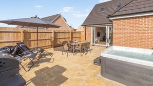 Un giardino sul retro con patio, arredi da esterno, vasca idromassaggio e recinzione in legno.