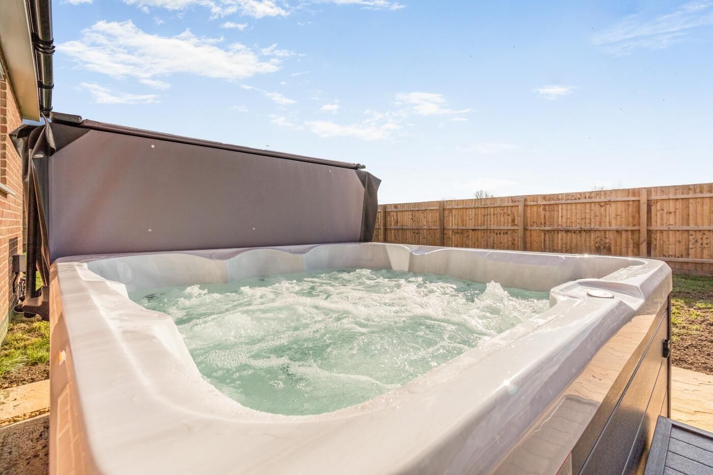 A hot tub with a wooden deck and a wooden fence in the background.