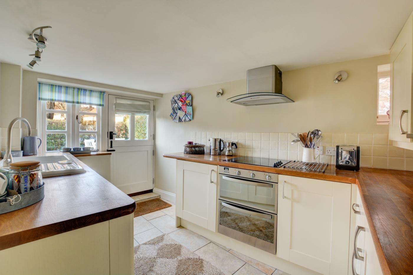 A kitchen with a wooden countertop, stainless steel appliances, and a window with a view of greenery.