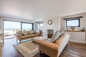 A spacious living room with a large window, a fireplace, and a kitchen area. - 5 Bed in Walmer (oc-do022) (Kingsdown)
