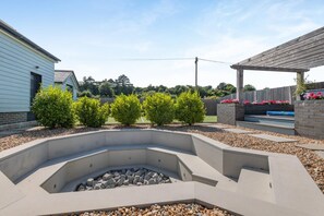 Un jardin aménagé avec un foyer extérieur, une pergola en bois et un mur de briques orné de fleurs.