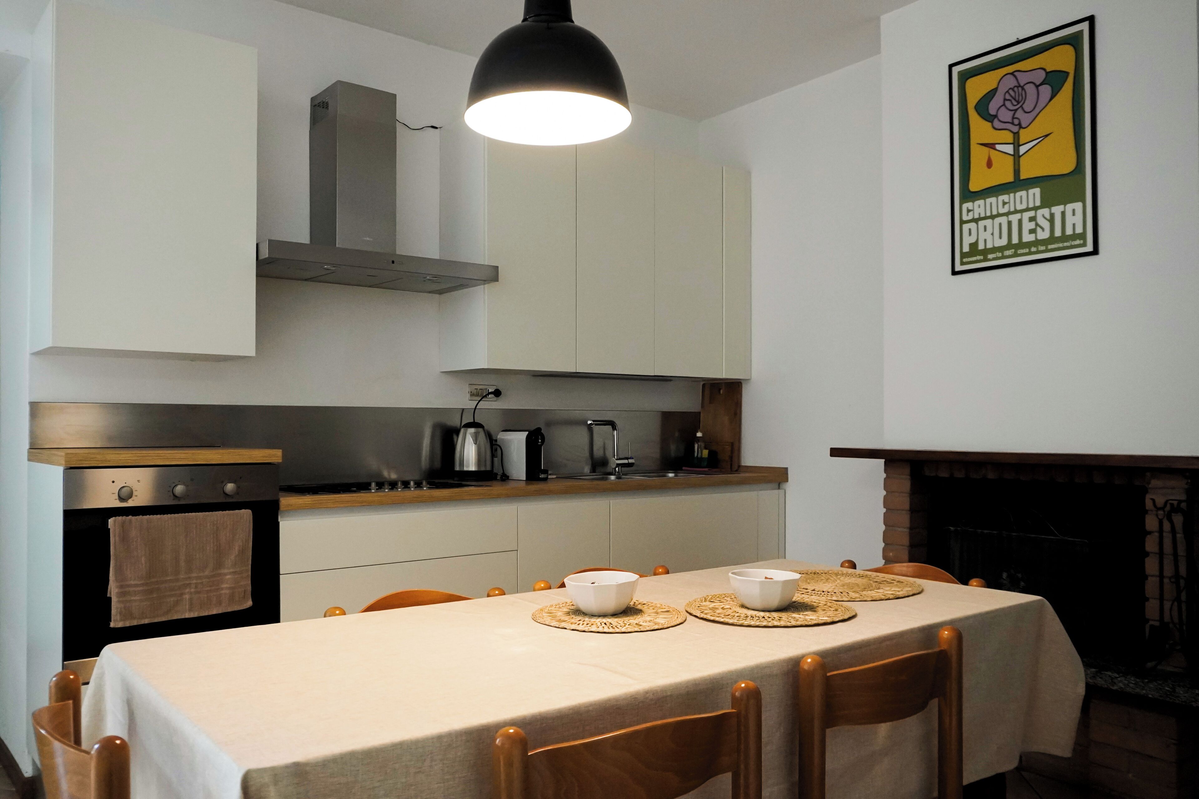 A dining area with a table set for two, a kitchen with modern appliances, and a fireplace.
