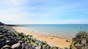 A beach with a rocky shoreline, calm sea, and a clear sky. - 2 Bed in Sheringham (oc-1540) (Sheringham)