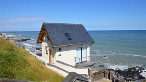A coastal house with a sloped roof, a balcony, and a view of the sea. - 2 Bed in Sheringham (oc-1540) (Sheringham)