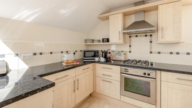 A modern kitchen with light wood cabinets, a gas stove, an oven, a microwave, and a toaster. - 2 Bed in Sidmouth (oc-t32948) (Sidmouth)