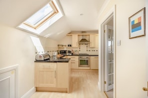 A modern kitchen with skylights, a central island, and a view into the adjacent room. - 2 Bed in Sidmouth (oc-t32948) (Sidmouth)