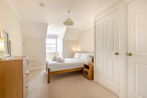 A bedroom with a bed, bedside tables, a dresser, a window, and a door. - 2 Bed in Sidmouth (oc-t32948) (Sidmouth)
