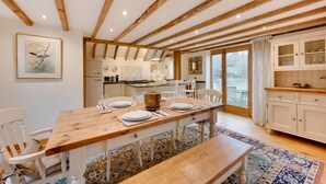 A dining area with a wooden table set for four, white chairs, and a bench. - 2 Bed in Guestling (oc-rh1142) (Westfield)