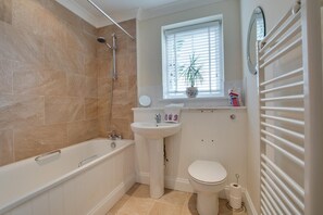 A bathroom with a bathtub, sink, toilet, and a window with blinds. - 3 Bed in Whitstable (oc-ek217) (Whitstable)