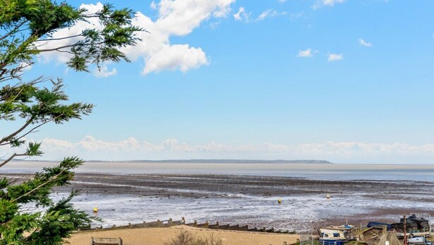 Vista costeira com praia de areia, um cais e céu limpo.