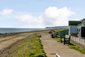 A coastal walkway with benches, a grassy area, and a view of the sea. - 2 Bed in Winchelsea (oc-rh1143) (Winchelsea Beach)