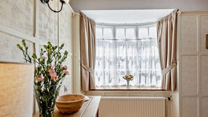 Una cocina con una mesa de madera, un florero con flores y una ventana con cortinas.