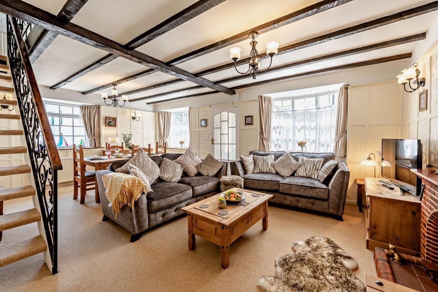 A spacious living room with a fireplace, a dining area, and a staircase.