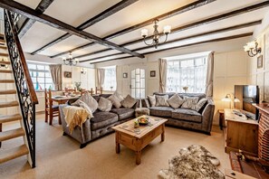 A spacious living room with a fireplace, a dining area, and a staircase. - 2 Bed in Ilfracombe (oc-quay) (Ilfracombe)