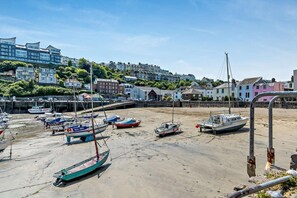 Uma marina costeira com barcos atracados numa praia arenosa, rodeada por edifícios coloridos.