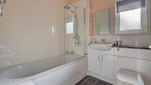 Ein modernes Badezimmer mit einer Duschkabine aus Glas, einer weißen Badewanne und einem Waschtisch mit Spiegel.