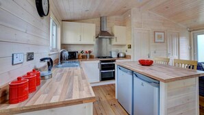 Eine kleine Küche mit Holzwänden, einer zentralen Kochinsel und einem Spülbecken.