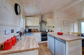 Una cucina compatta con pareti in legno, un'isola centrale e un lavello.