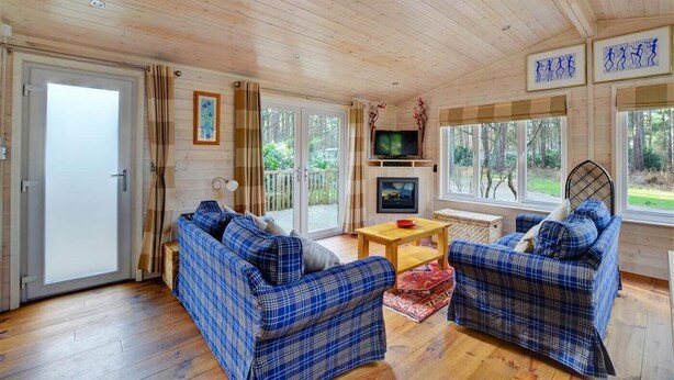 Eine Hütte mit zwei karierten Sofas, einem Fernseher und einer Holzbalkendecke.