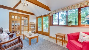A cozy room with a wooden ceiling, a red sofa, a wooden table, and a window with a view of trees. - 3 Bed in Hartfield (oc-tw653) (Hartfield)