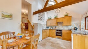 A kitchen with wooden cabinets, a dining table with chairs, a microwave, and a sink. - 3 Bed in Hartfield (oc-tw653) (Hartfield)