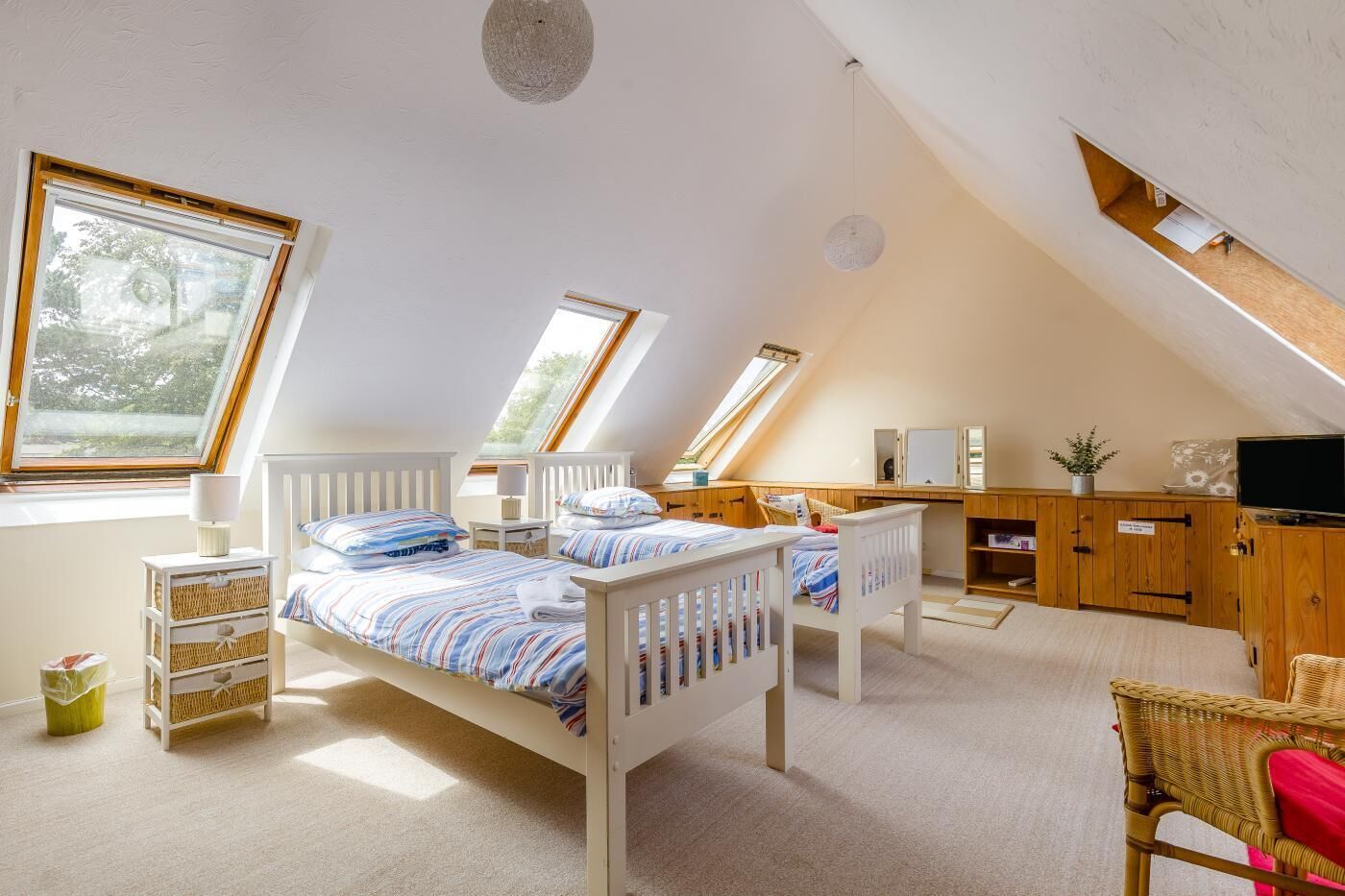 Une chambre avec deux lits, un bureau, une télévision et une fenêtre.