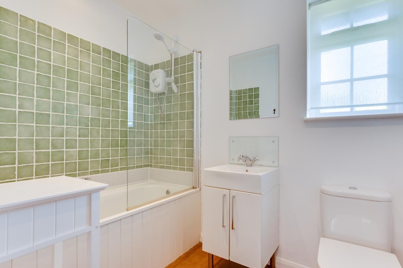 Un bany amb dutxa tancada amb vidre, un lavabo blanc i un vàter.