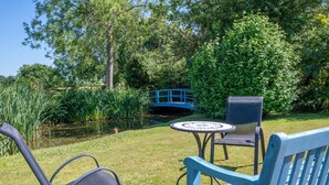 Un giardino con uno stagno, un ponte blu e un'area relax con tavolo e sedie.