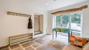 Um quarto amplo com piso de pedra, um banco, uma mesa de futsal e uma porta de madeira.