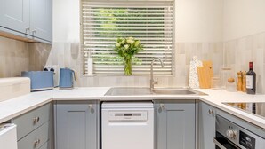 Una cocina moderna con lavavajillas, horno y ventana con persianas.