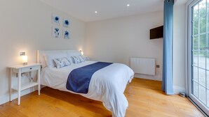 Un dormitorio con cama, mesita de noche, decoración en la pared y una ventana con cortinas.