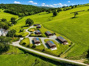 A rural property with multiple cabins, a winding road, and a large forested hill in the background.