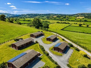 A rural property with multiple farm buildings, a gravel driveway, and expansive green fields.