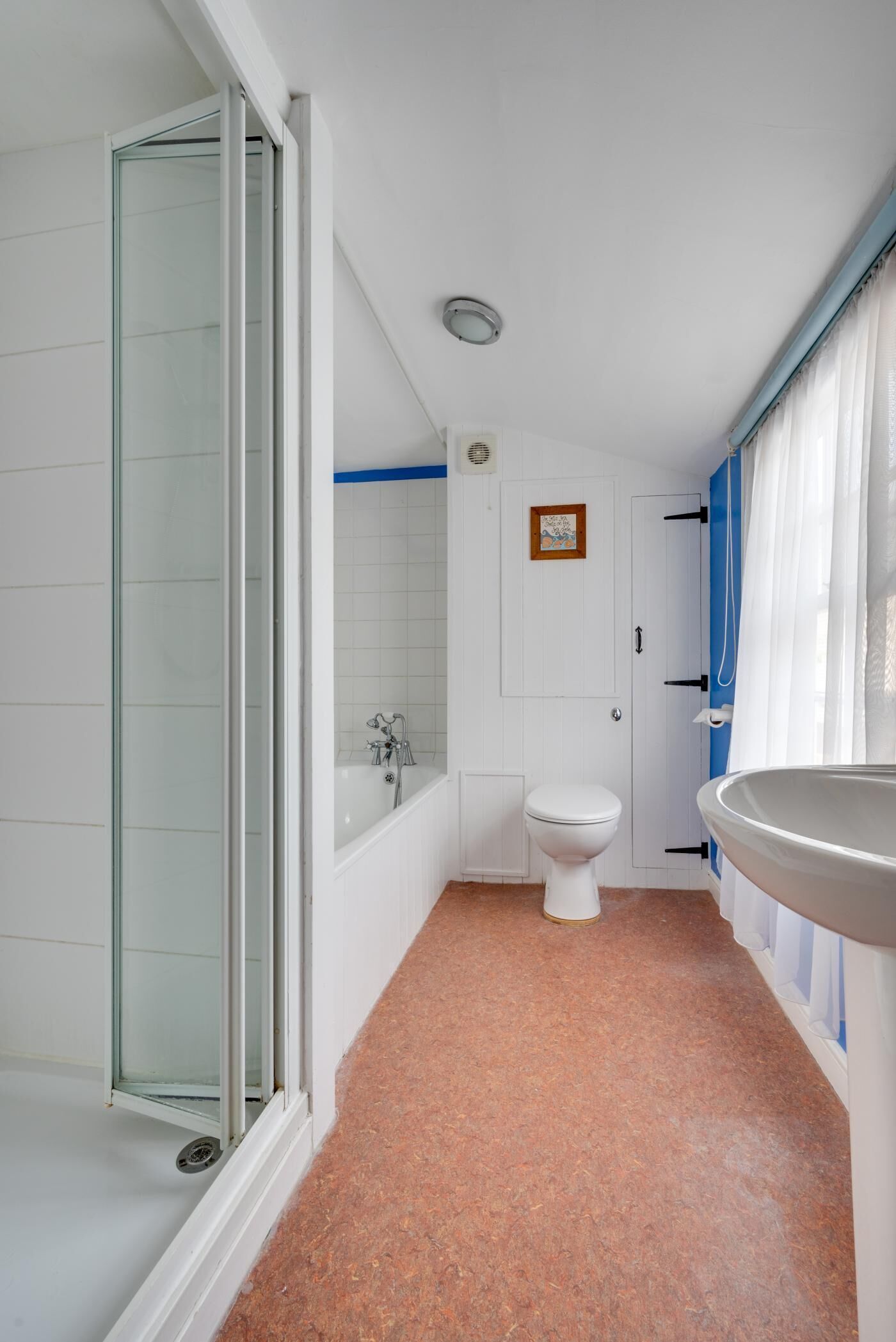 A bathroom with a glass shower enclosure, a bathtub, a toilet, and a sink.