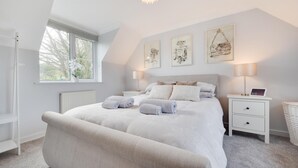 Une chambre à coucher avec un grand lit, une table de chevet, une lampe et des œuvres d’art accrochées au mur.