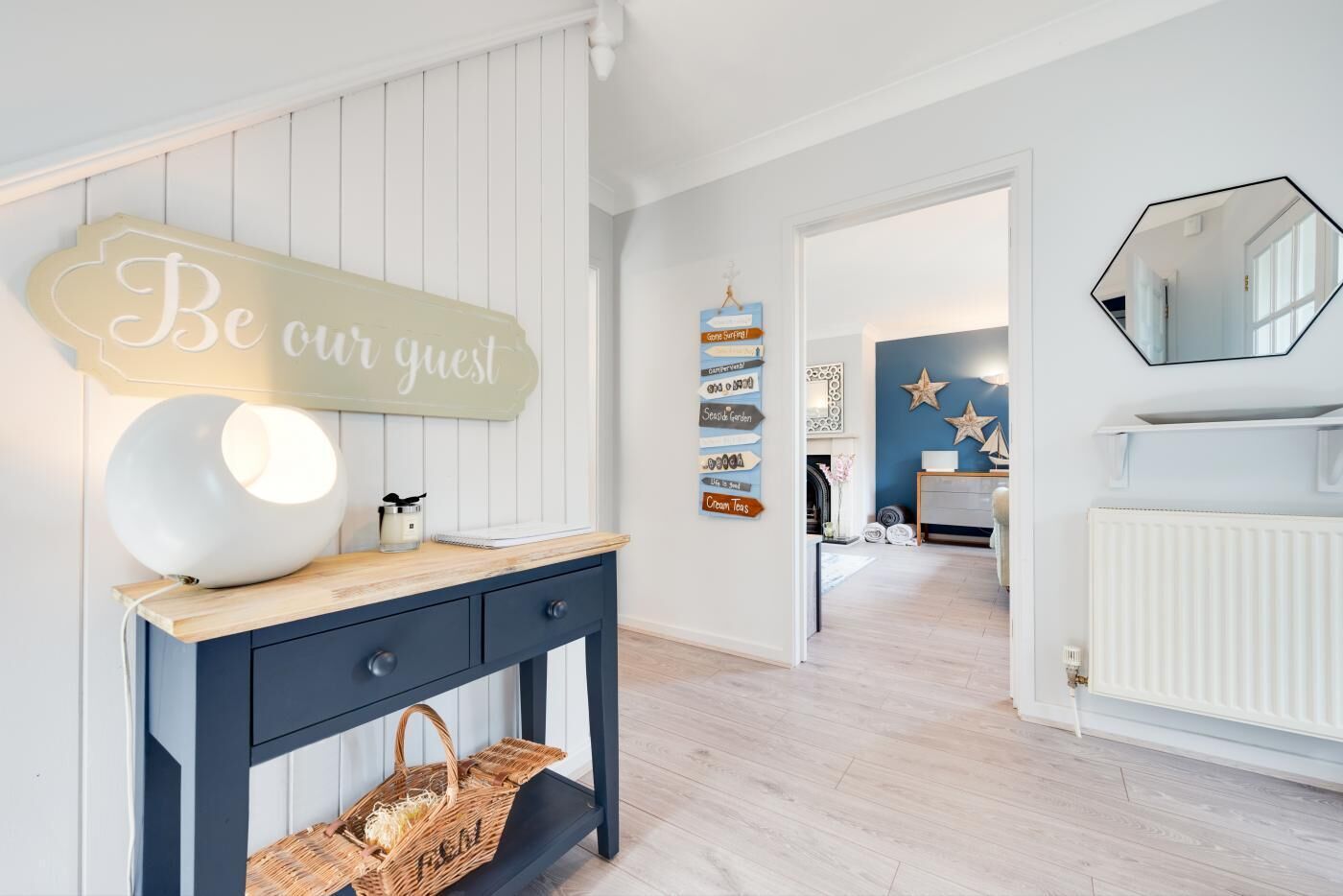 A modern hotel lobby with a welcoming sign, a stylish console table, and a view into the room area.