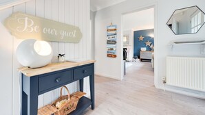 Un hall d'hôtel moderne, avec un panneau d'accueil, une console élégante et une vue sur l'espace des chambres.