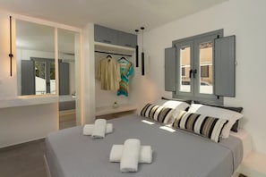A modern bedroom with a large bed, grey bedding, a wardrobe, and a mirror. - LInea Luxury Suites (Fira)