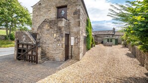 A stone building with a staircase leading to a door, a gravel driveway, and a green structure in the background. - 3 Bed in Carperby (oc-ds1033) (Carperby)