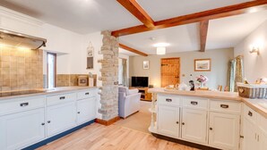 A spacious kitchen with white cabinets, a stone column, wooden beams, and a dining area with a sofa and table. - 3 Bed in Carperby (oc-ds1033) (Carperby)