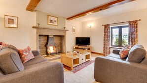 A cozy living room with a fireplace, two sofas, a TV, and a window with curtains. - 3 Bed in Carperby (oc-ds1033) (Carperby)