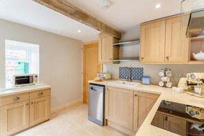 A modern kitchen with wooden cabinets, a dishwasher, a microwave, and a coffee machine. - 2 Bed in Summerbridge (oc-o32940) (Hartwith cum Winsley)